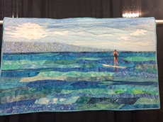 "Peaceful Paddling" by Babette Galinak from Flemington, NJ. Hand appliqued, machine pieced, machine quilted, original design. Babette writes: The spirit of nature influences my quilting. Immersing myself in our beautiful natural world as often as possible through hiking, kayaking, SUPing, etc. provides quiet time to dream about new quilting projects and allow the natural world to influence my work. The inspiration for Peaceful Paddling came from a perfect afternoon of paddling in Maui. Organic shapes, tropical batiks, a little glitter and a "hidden" quilt block merge the spirit of nature and quilting.